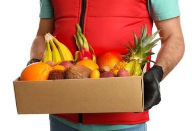 Photo of Courier holding box with assortment of exotic fruits on white background, closeup