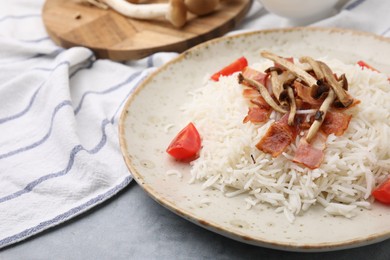 Photo of Delicious rice with bacon, mushrooms and tomatoes on table, closeup