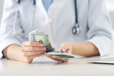 Photo of Doctor with bribe at desk in clinic, closeup. Corrupted medicine