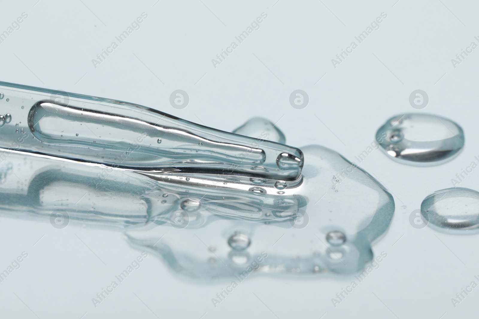 Photo of Glass pipette and transparent liquid on light background, closeup