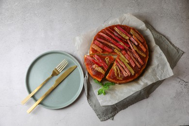 Photo of Freshly baked rhubarb pie and cutlery on light grey table, flat lay