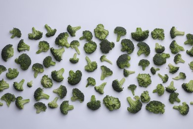 Photo of Many fresh green broccoli pieces on white background, flat lay