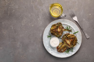 Photo of Plate with tasty grilled artichoke served on grey table, flat lay. Space for text