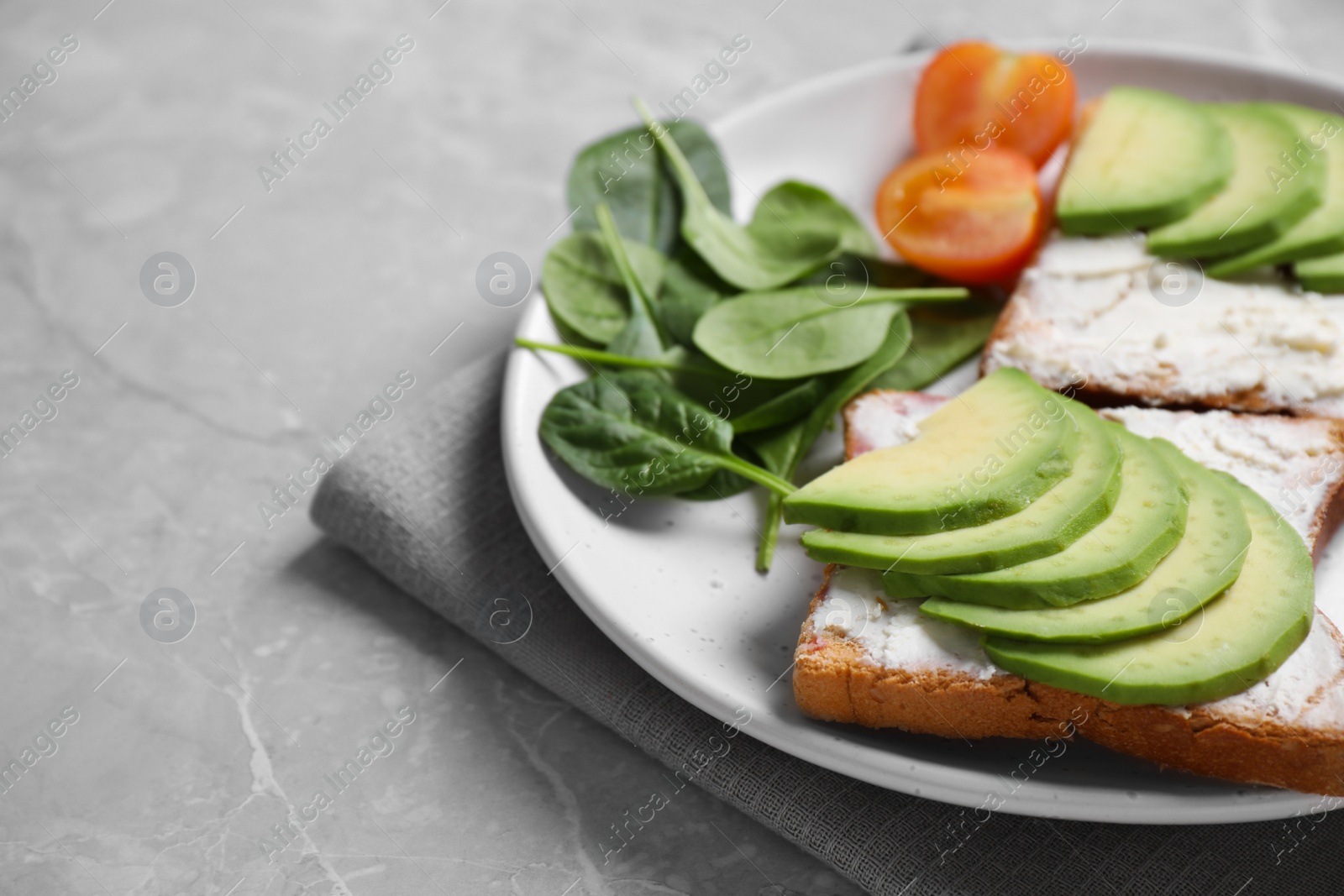 Photo of Sandwiches with avocado and spinach served on grey table, closeup. Space for text