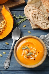 Photo of Delicious pumpkin soup in bowl on blue wooden table, flat lay