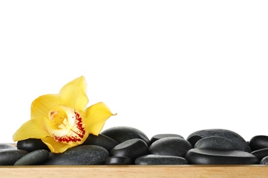 Photo of Wooden tray with spa stones and orchid flower against white background
