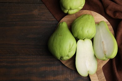 Photo of Cut and whole chayote on wooden table, flat lay. Space for text