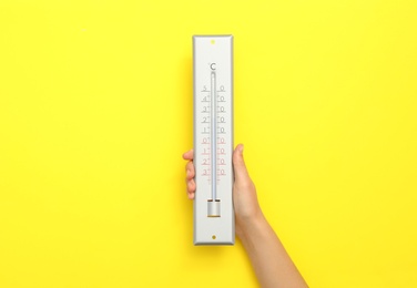 Photo of Woman with weather thermometer on yellow background, closeup