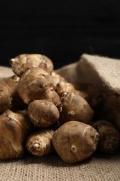 Photo of Jerusalem artichokes on bag against dark background, closeup