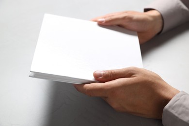 Photo of Man holding blank book at light grey table, closeup. Mockup for design