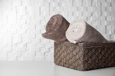 Photo of Basket with soft bath towels on table. Space for text