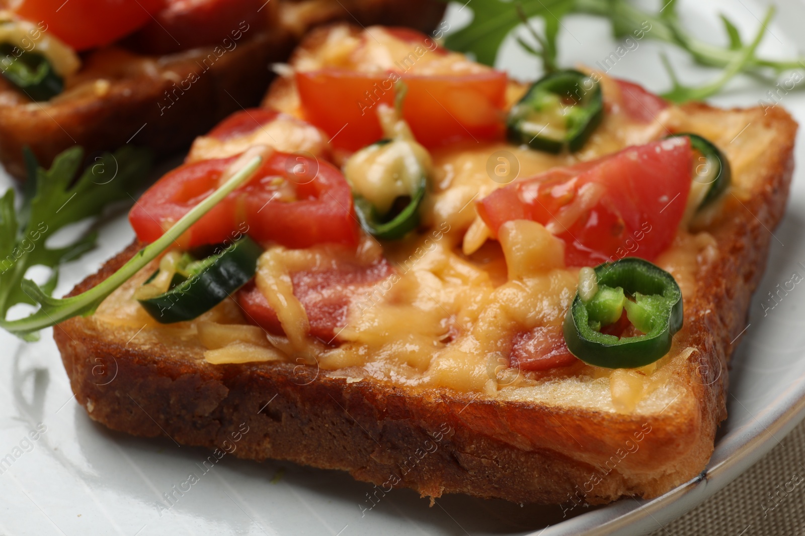 Photo of Tasty pizza toast and fresh arugula on plate, closeup