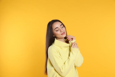 Photo of Beautiful young woman wearing warm sweater on yellow background