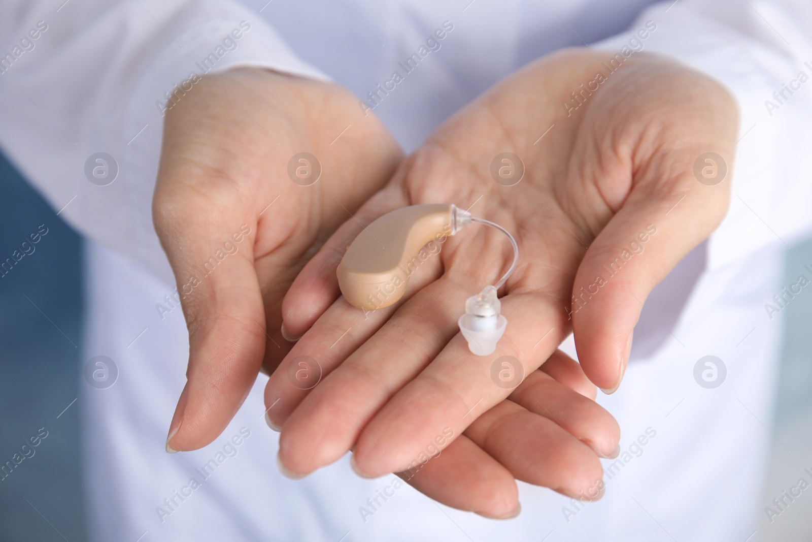 Photo of Doctor holding hearing aid, closeup. Medical device