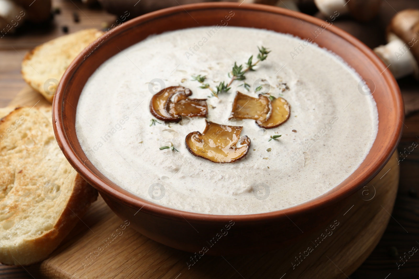 Photo of Fresh homemade mushroom soup in ceramic bowl on wooden table, closeup