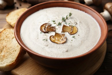 Photo of Fresh homemade mushroom soup in ceramic bowl on wooden table, closeup