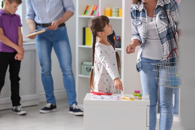 Photo of Little girl with mother choosing school stationery in store