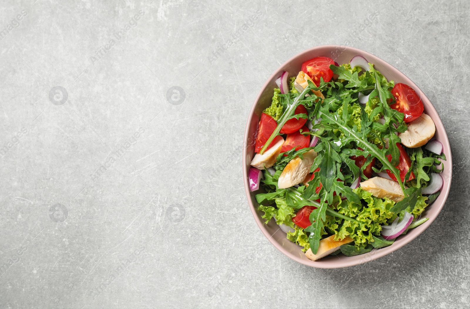 Photo of Delicious salad with chicken, arugula and tomatoes on grey table, top view. Space for text