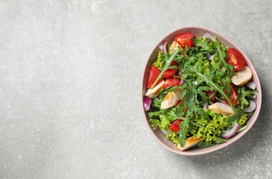Photo of Delicious salad with chicken, arugula and tomatoes on grey table, top view. Space for text