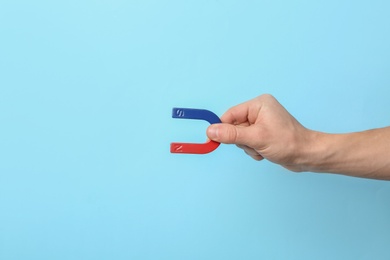 Photo of Man holding magnet on color background, closeup. Space for text
