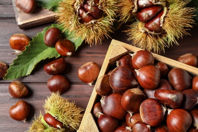 Photo of Fresh sweet edible chestnuts on wooden table, flat lay