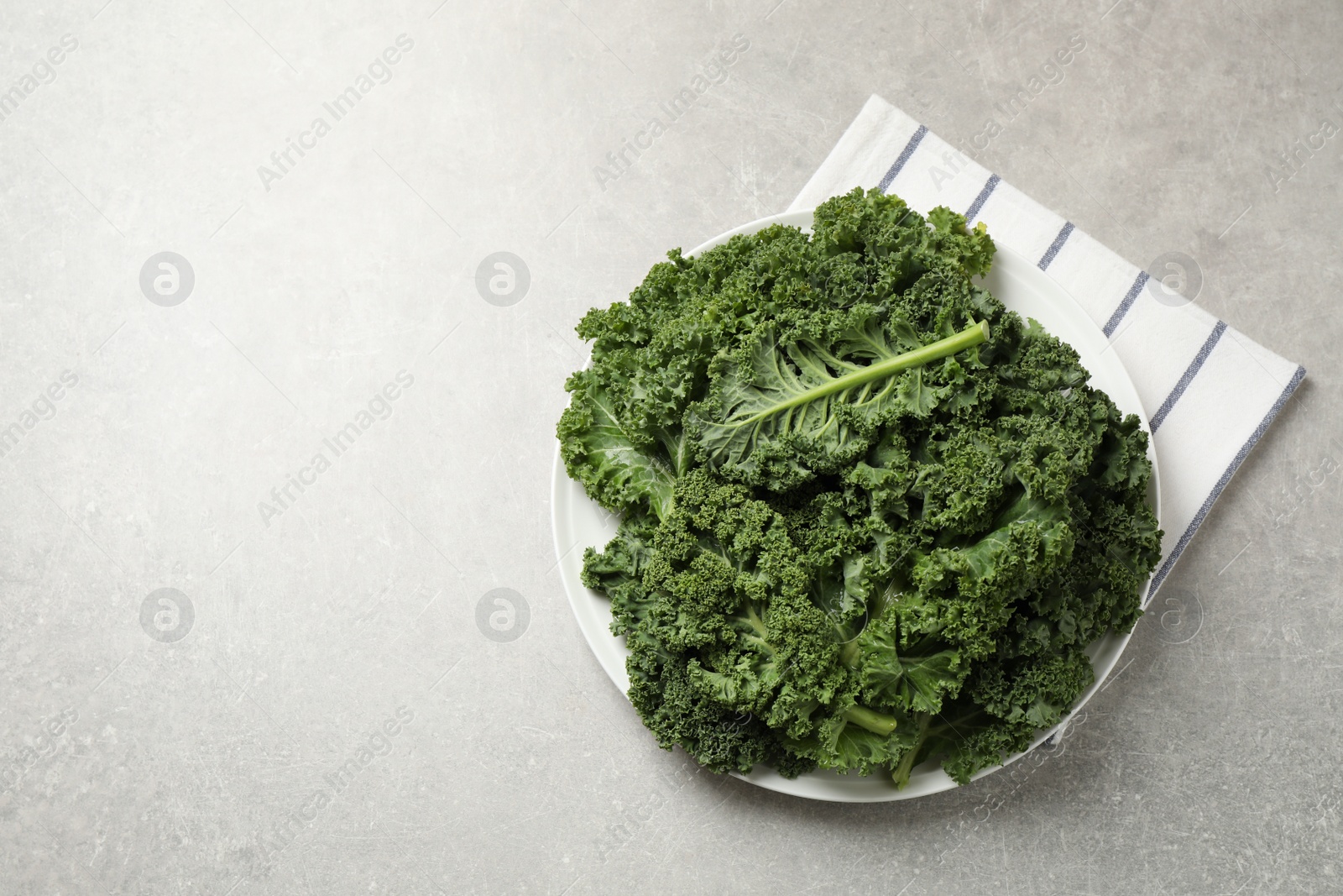 Photo of Fresh kale leaves on grey table, flat lay. Space for text