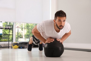Photo of Athletic man doing push ups with medicine ball in modern gym