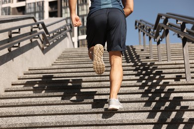Photo of Man running up stairs outdoors on sunny day, closeup