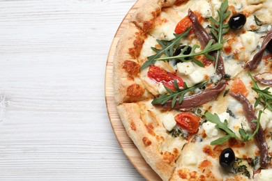 Photo of Tasty pizza with anchovies, arugula and olives on white table, top view. Space for text