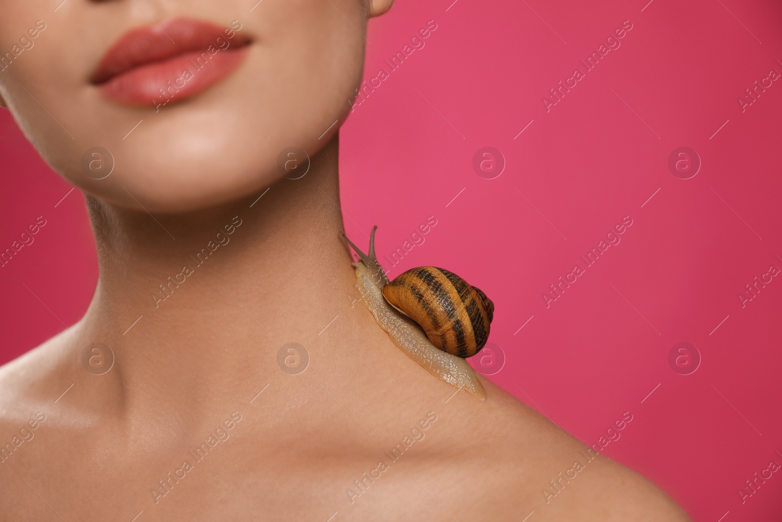 Photo of Beautiful young woman with snail on her neck against pink background, closeup