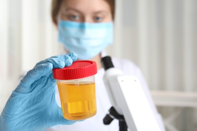 Photo of Doctor holding container with urine sample for analysis