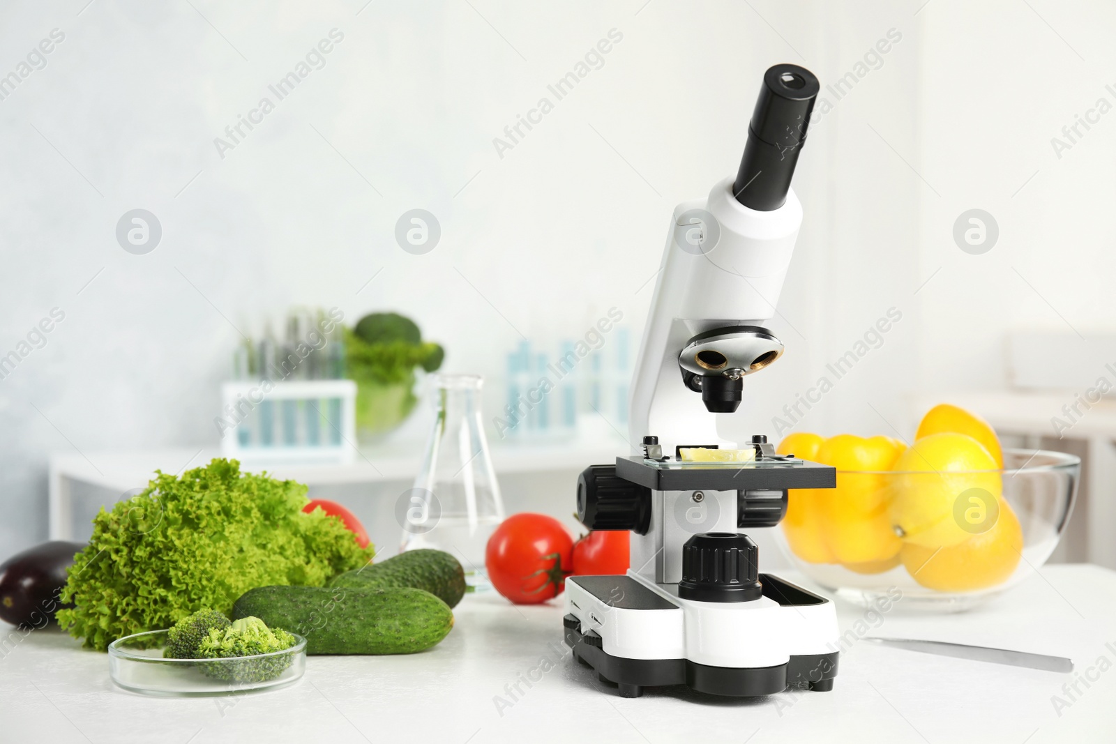 Photo of Microscope and fresh vegetables on table in laboratory. Poison detection