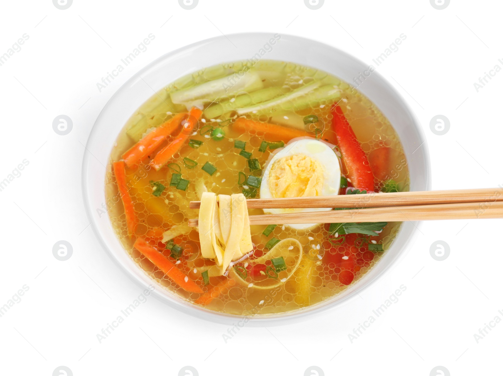 Photo of Chopsticks with noodles over bowl of tasty ramen on white background