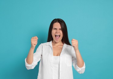 Photo of Aggressive young woman shouting on turquoise background