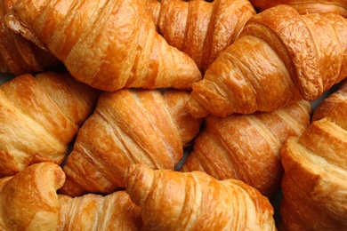 Photo of Fresh tasty croissants as background, closeup. French pastry