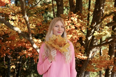 Photo of Portrait of beautiful young woman with autumn leaves in forest