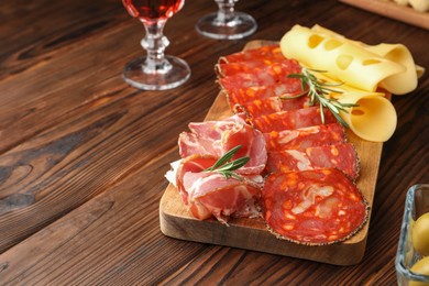 Photo of Delicious charcuterie board served on wooden table, space for text