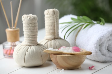 Photo of Beautiful spa composition with herbal bags, sea salt and reed air freshener on white wooden table, closeup
