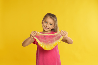 Photo of Little girl with slime on yellow background