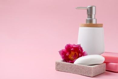 Photo of Soap bar and bottle dispenser on pink background, space for text