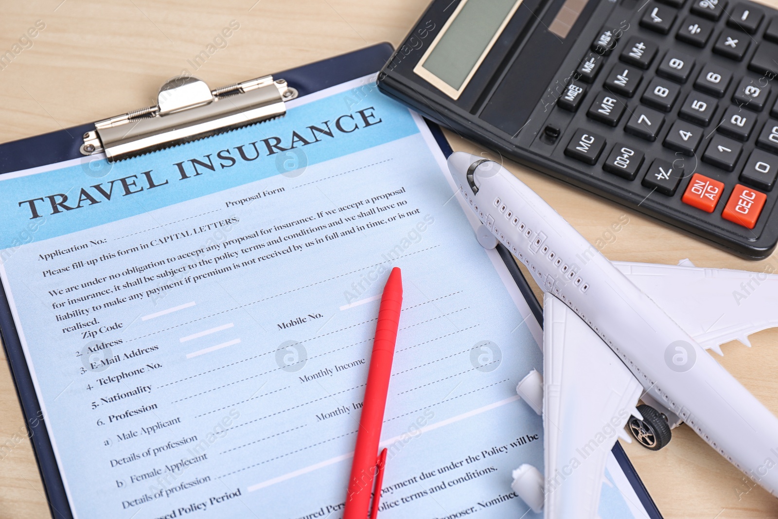 Photo of Composition with toy plane, calculator and travel insurance form on table