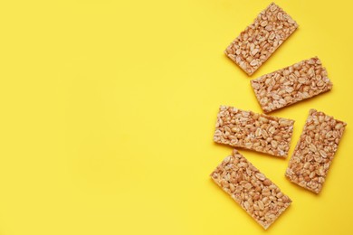 Photo of Tasty peanut bars (kozinaki) on yellow background, flat lay. Space for text