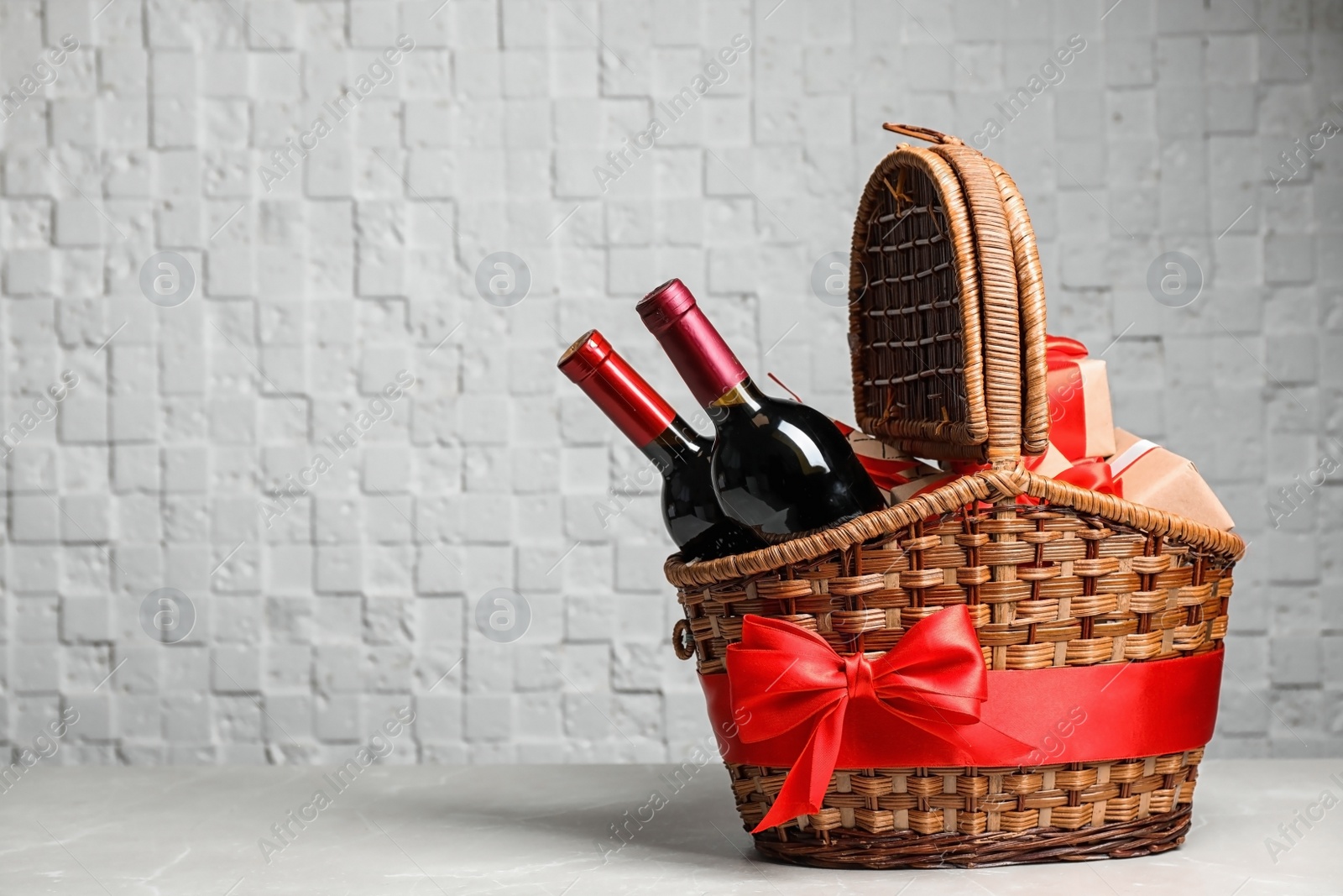 Photo of Gift basket with bottles of wine on light background. Space for text