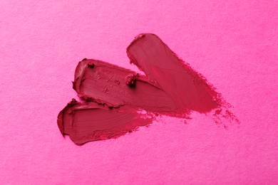 Photo of Smears of beautiful lipstick on pink background, top view