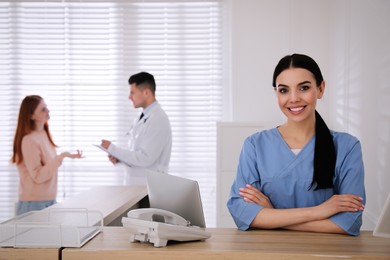 Photo of Receptionist working at countertop while talking with patient in hospital
