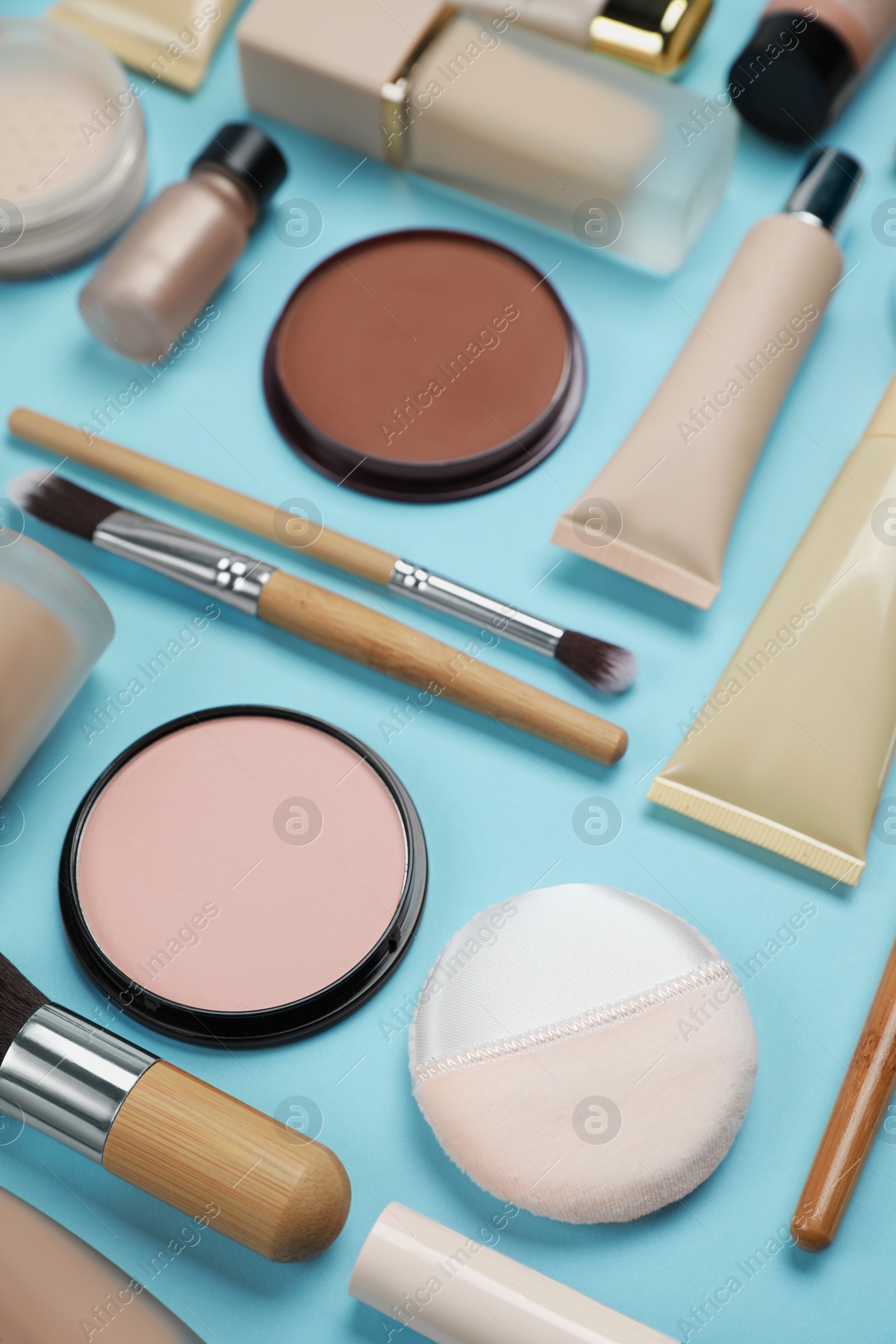 Photo of Face powders and other decorative cosmetic products on light blue background