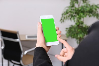 Woman using smartphone with green screen indoors, closeup. Gadget display with chroma key. Mockup for design