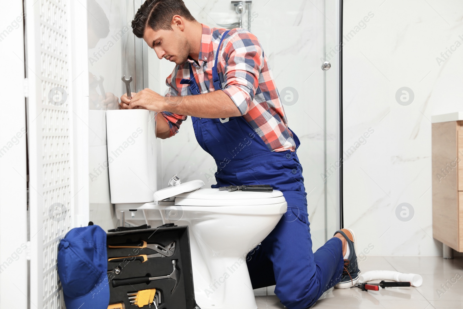 Photo of Professional plumber working with toilet bowl in bathroom