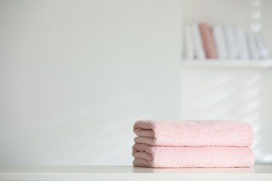 Stack of clean soft towels on white table indoors. Space for text