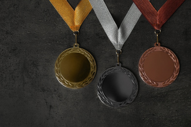 Gold, silver and bronze medals on grey stone background, flat lay. Space for design